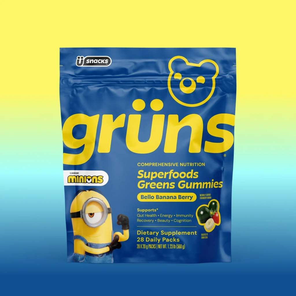 Blue Grüns Superfoods Greens Gummies bag in Bello Banana Berry flavor with Minions branding, on a yellow-to-blue gradient background