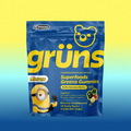 Blue Grüns Superfoods Greens Gummies bag in Bello Banana Berry flavor with Minions branding, on a yellow-to-blue gradient background
