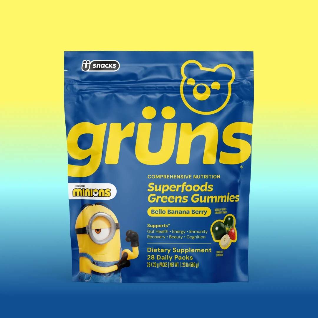 Blue Grüns Superfoods Greens Gummies bag in Bello Banana Berry flavor with Minions branding, on a yellow-to-blue gradient background