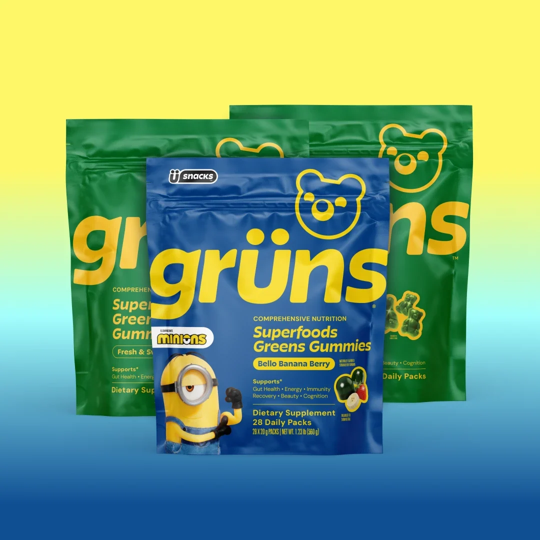 Three Grüns Superfoods Greens Gummies bags in green Original flavors and blue Bello Banana Berry with Minions branding, on a yellow-to-blue gradient background