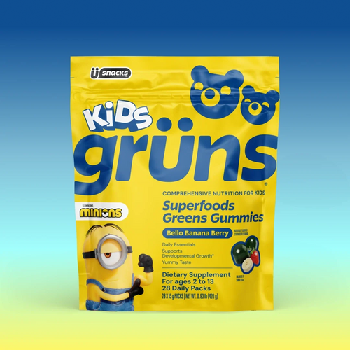 A yellow bag of Kids Grüns Superfoods Greens Gummies in "Bello Banana Berry" flavor features a Minions character on the front, labeled as a dietary supplement for ages 2 to 13 with 28 daily packs, set against a blue-to-yellow gradient background.