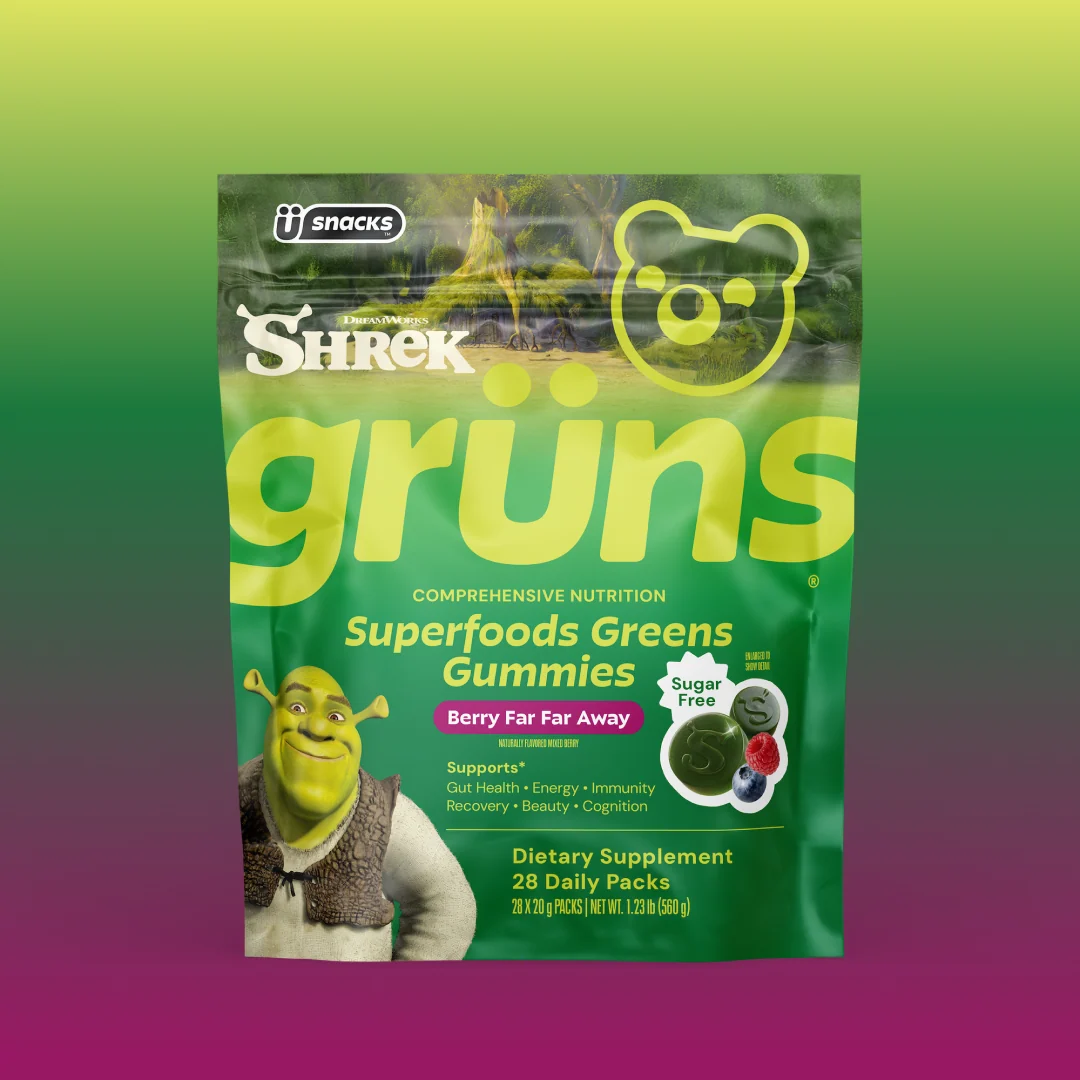 Green Grüns Superfoods Greens Gummies package featuring the Shrek logo and character, labeled Berry Far Far Away flavor with a Sugar Free badge, listing support for gut health, energy, immunity, recovery, beauty, and cognition, Dietary Supplement, 28 Daily Packs, on a green-to-purple gradient background.