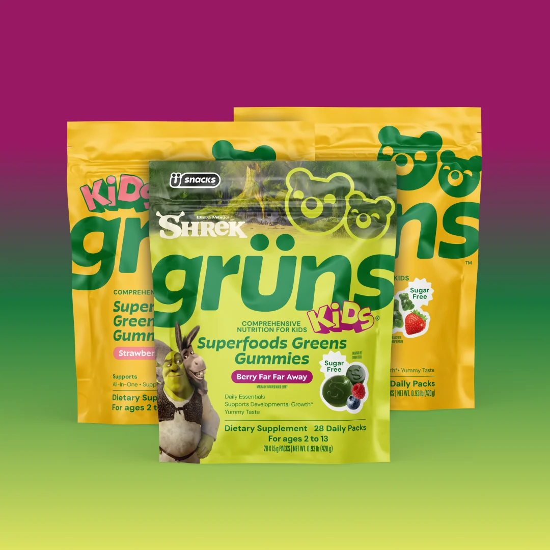 Three overlapping Kids Grüns Superfoods Greens Gummies packages, front pack featuring Shrek and Donkey and labeled Berry Far Far Away flavor with a Sugar Free badge, yellow packs behind, on a purple-to-green gradient background.